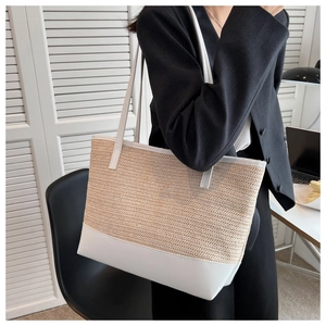 Close-up of a woven tote bag featuring beige straw texture and white leather bottom accents