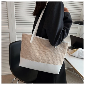 Detailed close-up of the woven straw texture and white leather strap of the tote bag