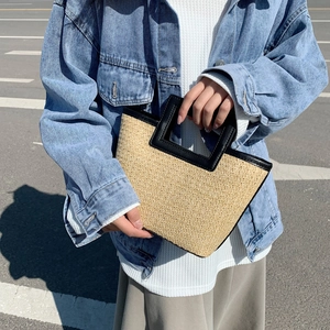 Fashionable woven straw tote bag with black leather handles for summer travel