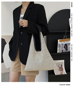 Close-up of a large beige woven tote bag with black leather straps on a female model
