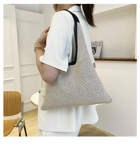 Detail of cream woven tote bag with a contrast black shoulder strap on model