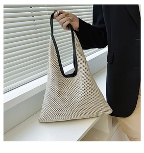 Close-up of cream woven handbag with black leather trim and triangular design