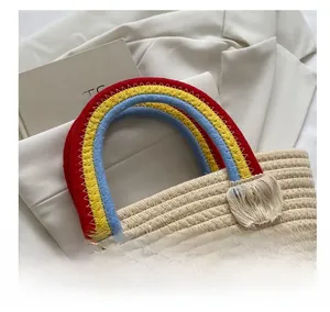 Close-up of rainbow gradient woven handles and tassel detail on straw handbag
