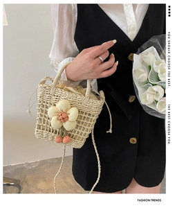 Detail of handmade cream straw bucket bag with floral charms and drawstring lining