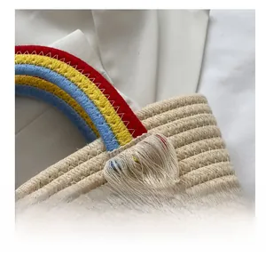Detail of straw woven bucket bag with rainbow braided handle and white tassel accent