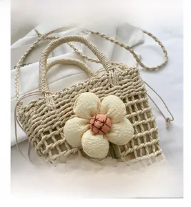 Detail of handmade straw bucket bag with floral decor and plush charms for summer beach