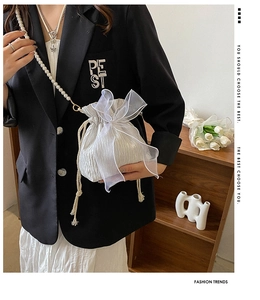 Detail of drawstring bucket bag with large organza bow and pearl chain strap