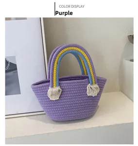 Detail of purple woven handbag featuring rainbow cord handle and white decorative tassels