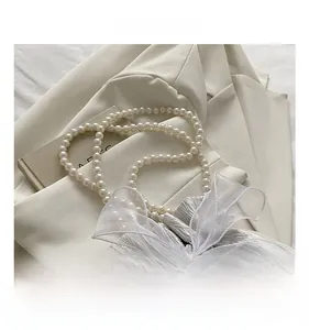 Detail of silver drawstring bucket bag with large organza bow and pearl chain handle