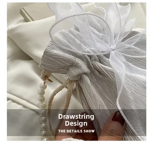 Detail of silver pleated bucket bag with pearl handle and organza bow accents