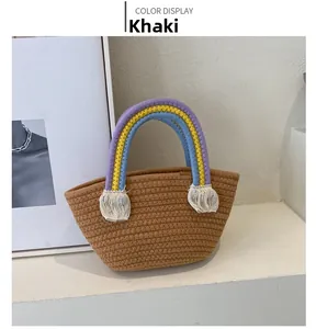 Detail of khaki woven tote bag featuring colorful rainbow handles and white tassels