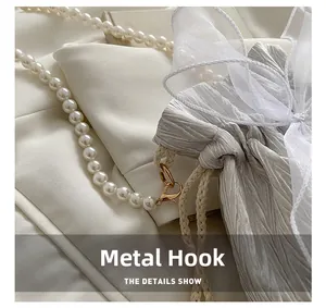 Close-up of elegant pearl strap and gold hardware hook on a white lace bucket bag