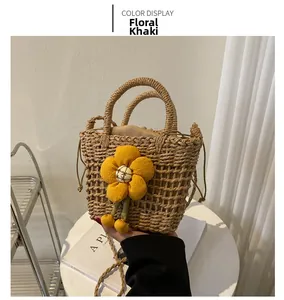 Detail of khaki straw bucket bag featuring a large yellow flower and drawstring closure