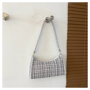 Détail d'un sac sous les bras en tweed noir et blanc avec fermeture éclair et forme lune