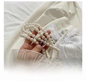 Detail of high-gloss white pearl shoulder strap with elegant design on a white blazer