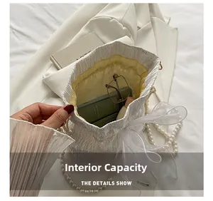 Internal capacity of the white pleated bucket bag showing phone and cosmetics