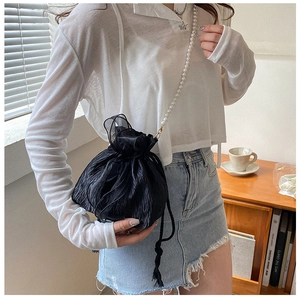 Detail of black pleated bucket bag with decorative lace trim and pearl chain strap