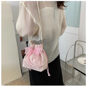 Detail of pink pleated drawstring bucket bag with large organza bow and pearl strap