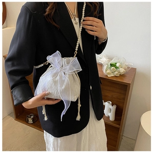 Detail of white pleated bucket bag featuring large organza bow and pearl chain strap