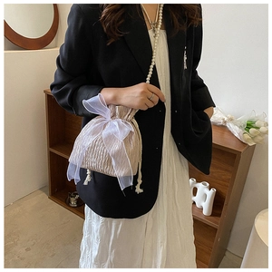 Detail of champagne pleated bucket bag with large organza bow and pearl chain strap