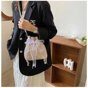 Detail of champagne bucket bag featuring a large organza bow and pearl shoulder strap