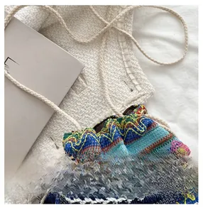 Détail du sac seau tissé bohème avec motifs colorés, glands et fermeture à cordon de serrage