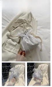Detail of white drawstring bucket bag with oversized organza bow and pearl chain strap