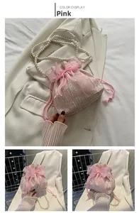 Detail of pink satin bucket bag with large bow decoration and pearl chain strap