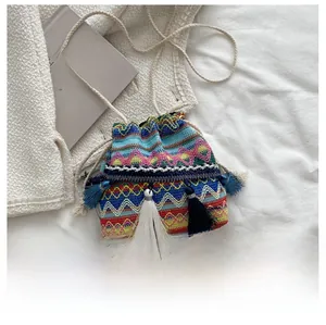 Détail du sac seau bohème tissé avec motifs géométriques et pompons multicolores vibrants
