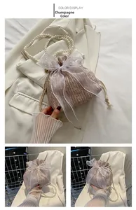 Detail of champagne pleated bucket bag with oversized lace bow and pearl handle