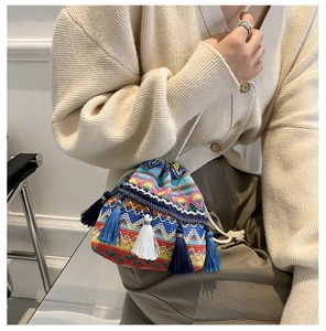 Détail du sac seau bohème avec motifs géométriques colorés et des glands bleus