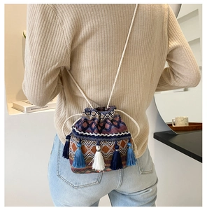 Détail du sac seau tissé ethnique avec motifs bohèmes et pompons suspendus bleus