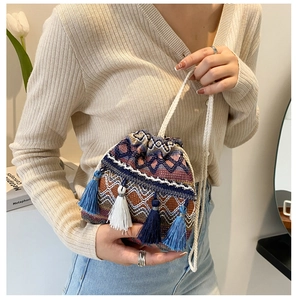 Détail d'un sac seau tissé ethnique avec motifs géométriques et franges à pompons