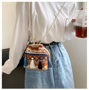 Détail du sac seau tissé bohème aux motifs orange et aux franges bleues