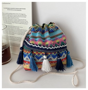 Détail d'un sac seau bohème avec motifs tissés colorés et pompons ethniques décoratifs