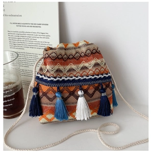 Détail d'un sac seau en tricot bohème avec motifs ethniques et glands multicolores