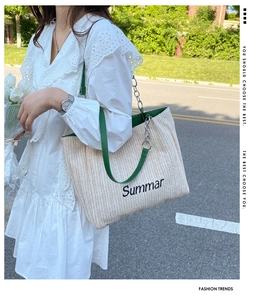 Detail of woven straw tote bag with green handles and metallic chain on a white dress