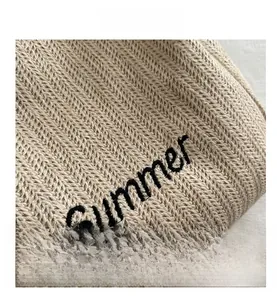 Detail of Summer letter embroidery on natural straw woven tote bag texture