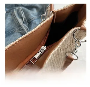 Detail shot of smooth silver metal zipper and woven texture on straw tote bag
