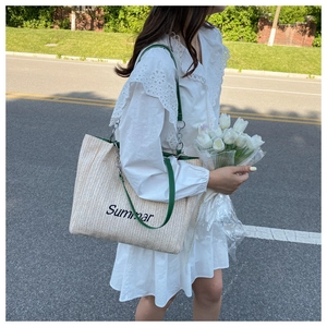 Detail of straw woven tote bag with Summer embroidery and green leather chain strap