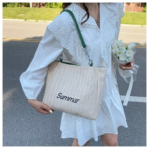 Detail of Summar embroidery and chain strap on a cream straw woven tote bag