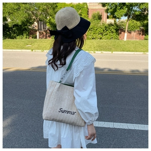 Detail of a beige straw tote bag with green leather straps and Summar embroidery