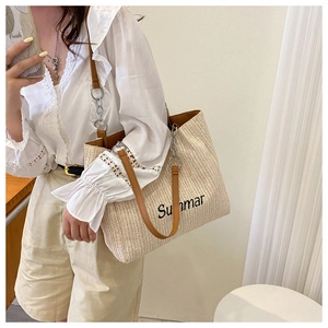 Detail of woven tote bag with Summar embroidery and leather chain strap shown on model