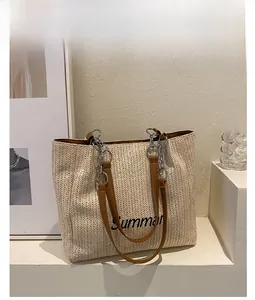 Detail of khaki straw tote bag with Summer embroidery and leather chain strap