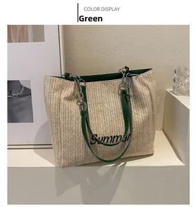 Detail view of large straw tote with Summer embroidery and green metal chain strap