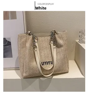 Close-up of white straw tote bag featuring umma embroidery and silver chain handle