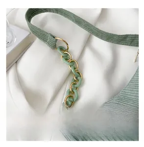 Detail of green corduroy shoulder strap with acrylic and gold metal ring links