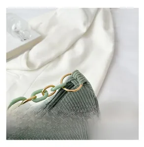 Detail of green corduroy bag showing resin chain and gold hardware with zipper closure