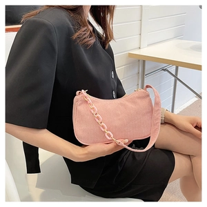 Detail of pink corduroy fabric texture and decorative acrylic chain on shoulder bag