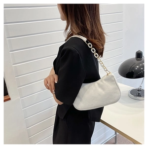Detail of white corduroy shoulder bag featuring trendy acrylic chain strap on model